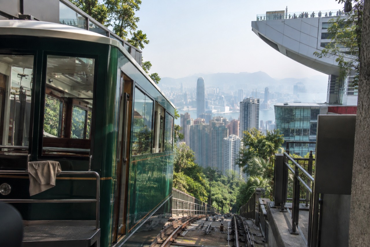 Green Peak Tram funicular car at the upper terminus building above Hong Kong skyscrapers