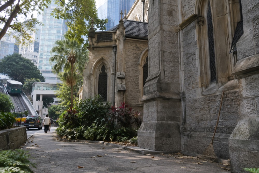 St John's Cathedral stone Gothic building beside a road with modern towers behind