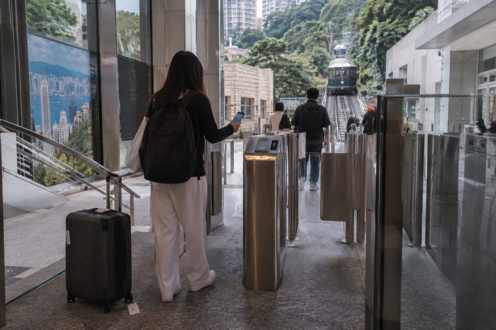 A pre-purchased ticket holder scanning a QR code on a phone at the admission gate of the Peak Tram terminus
