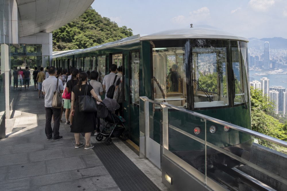 The green sixth-generation Peak Tram car at the upper terminus platform with passengers boarding