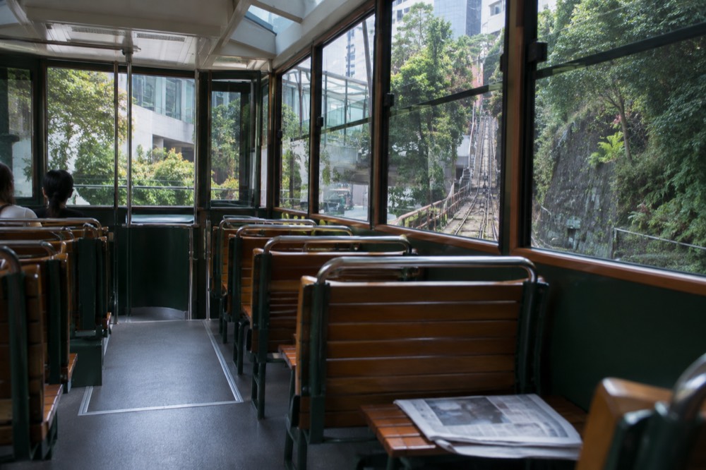 Interior of a green Peak Tram car with panoramic windows and rows of seats