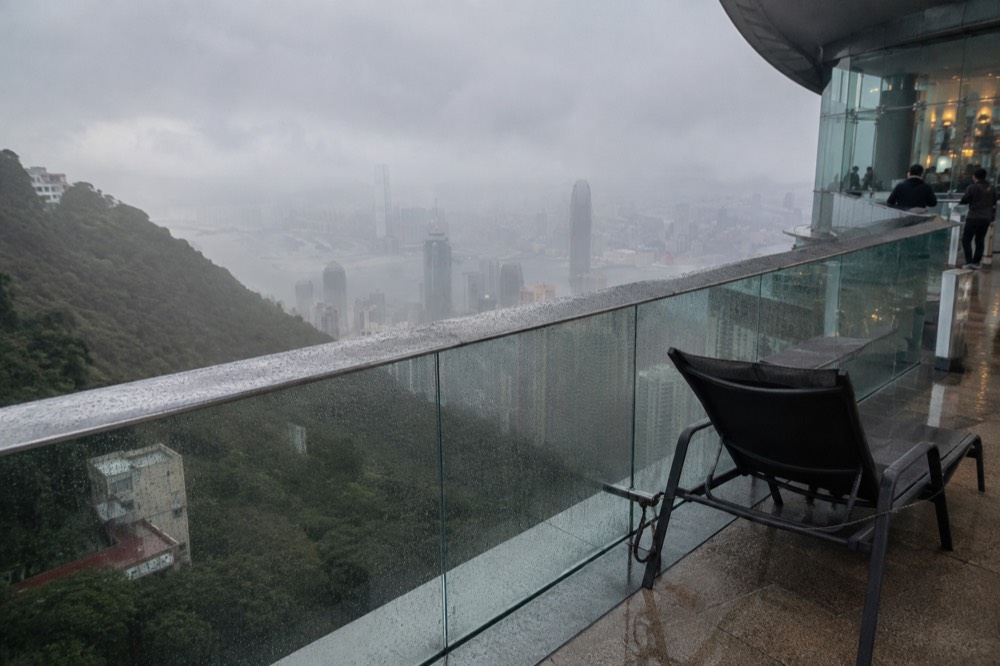 Glass railing of an elevated deck with a hazy skyline below
