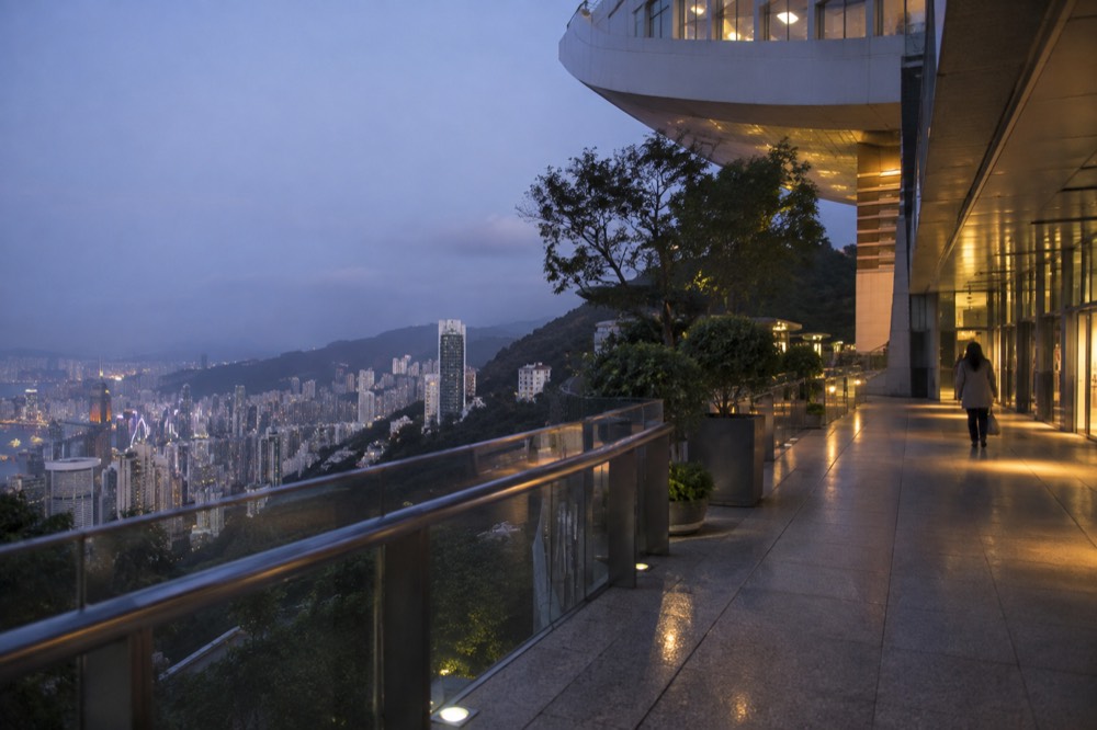 Elevated walkway above a city at dusk with lights beginning to glow