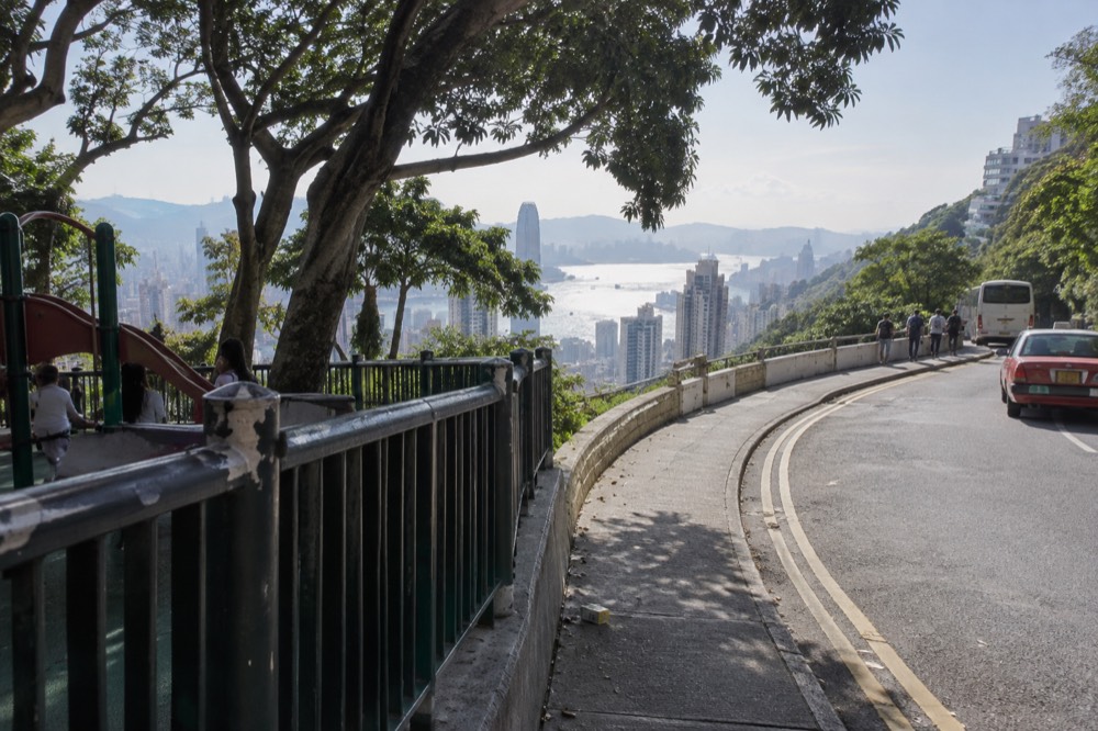 Trees and a walking path along a hillside road above Hong Kong harbour
