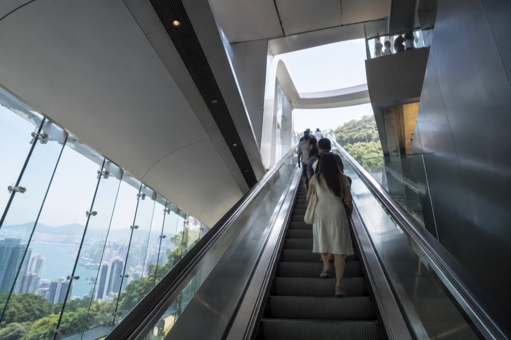 Interior escalators inside a hilltop viewing tower leading up toward a rooftop deck
