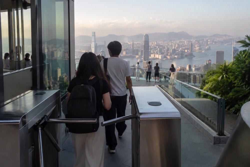 A ticket gate at a rooftop observation deck entrance with visitors passing through