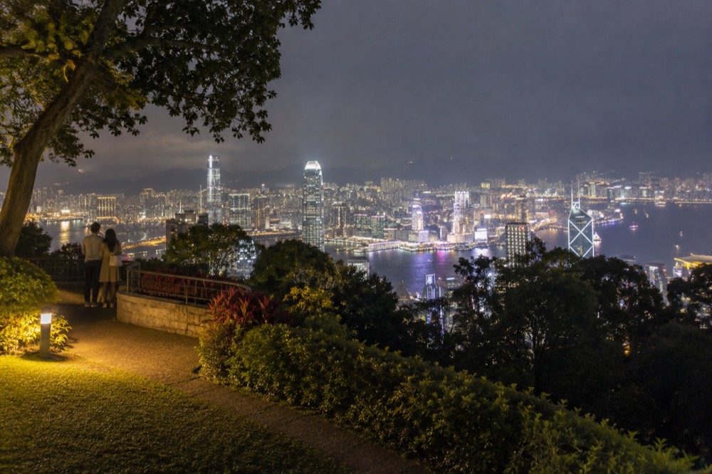 illuminated Hong Kong skyline across Victoria Harbour seen from high ground at night
