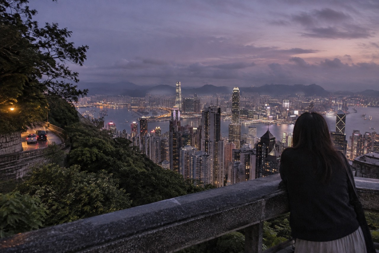 Hong Kong skyline and harbour lights seen from a hillside viewpoint at dusk