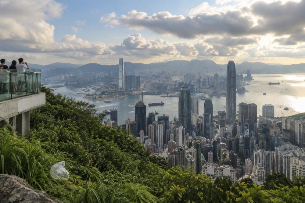 Panorama of dense Hong Kong skyscrapers and harbour shipping under a partly cloudy sky