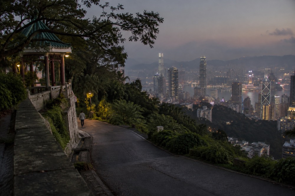 Evening lights of Hong Kong spreading below the Peak road and green hillsides