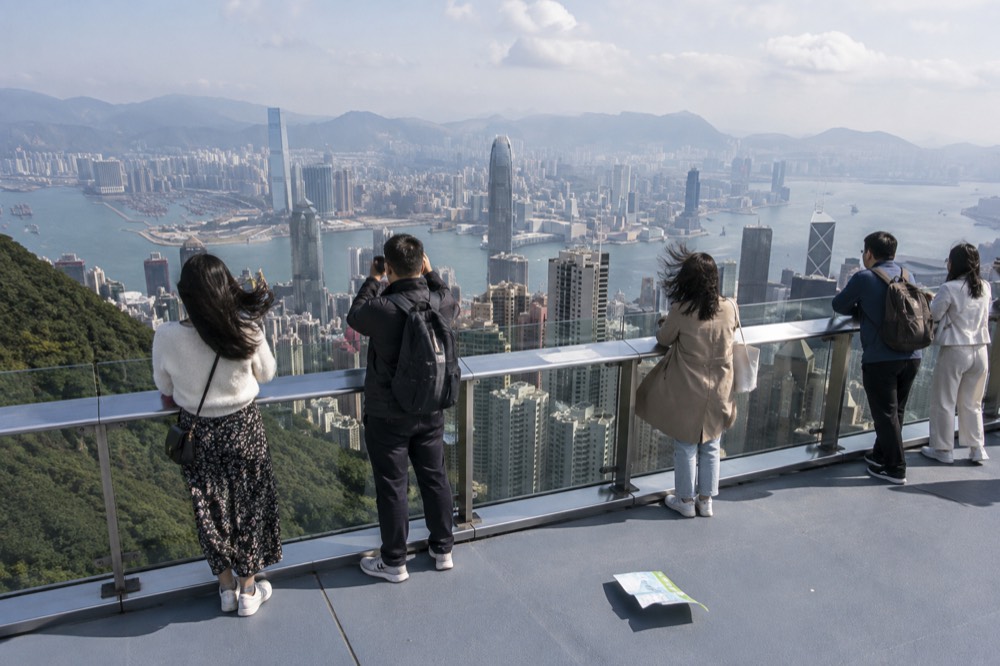 Observation deck on a tower roof with visitors at the railing and city towers below