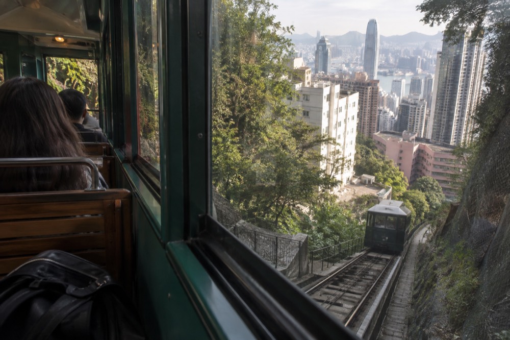 Tall apartment towers seen from the funicular window appearing to tilt against the hillside