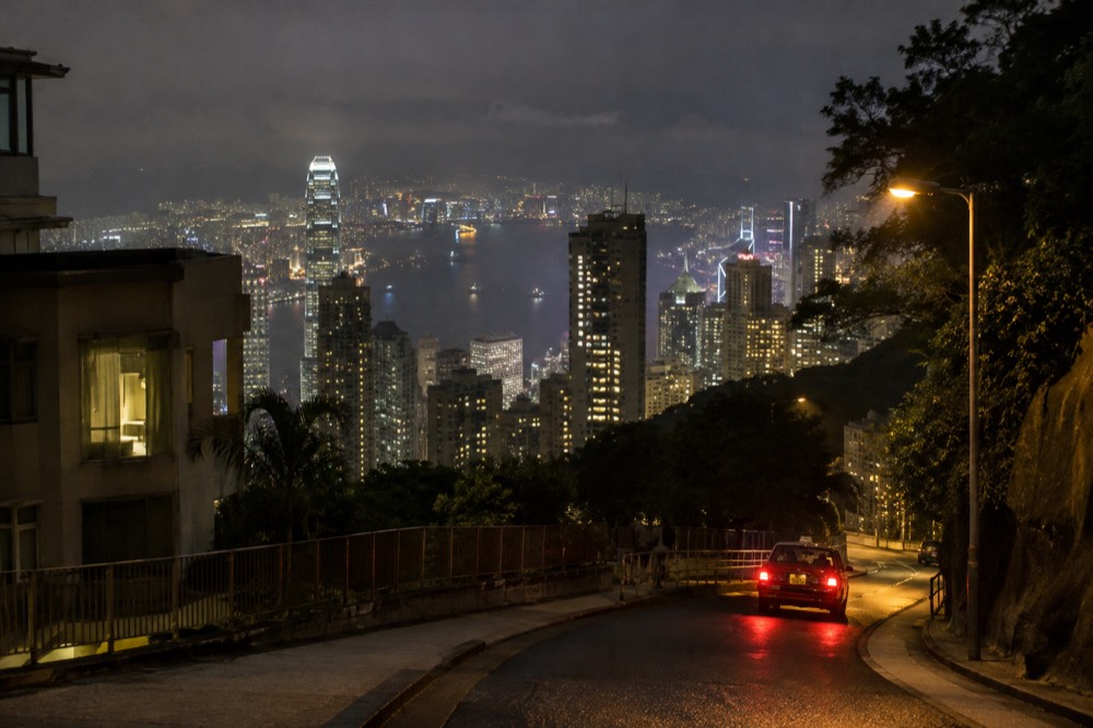 Illuminated Hong Kong skyline and harbour at night seen from a high roadside viewpoint