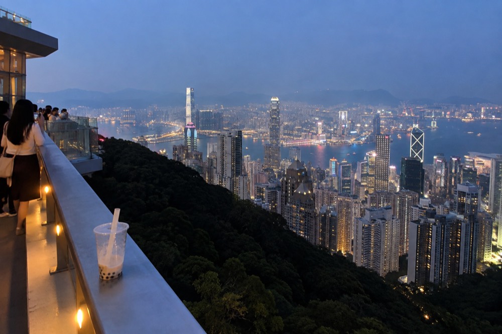 Rooftop viewing platform at dusk with the city skyline and harbour spread below