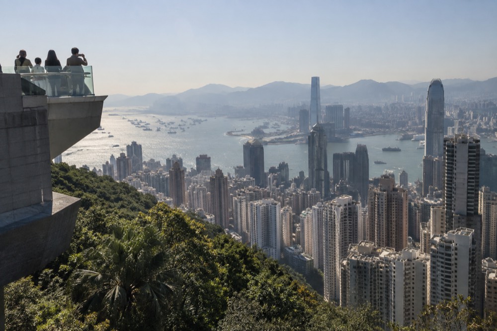 View from a high rooftop over dense city towers and a wide harbour