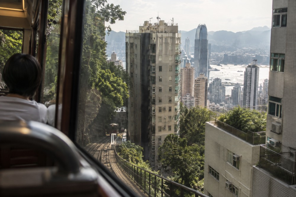 View through a Peak Tram window of Hong Kong apartment blocks and harbour beyond