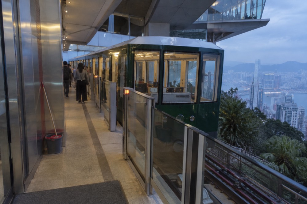 Modern green funicular tramcar at a rebuilt station platform with glass doors