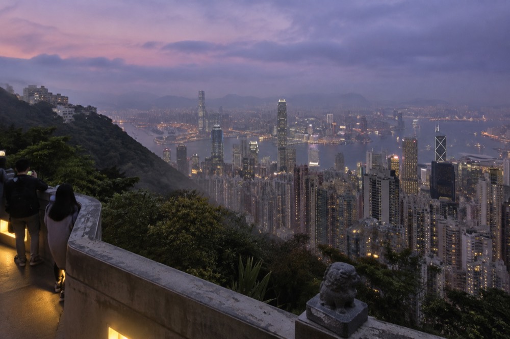 A panoramic view over Hong Kong harbour and towers seen from high green ground at dusk