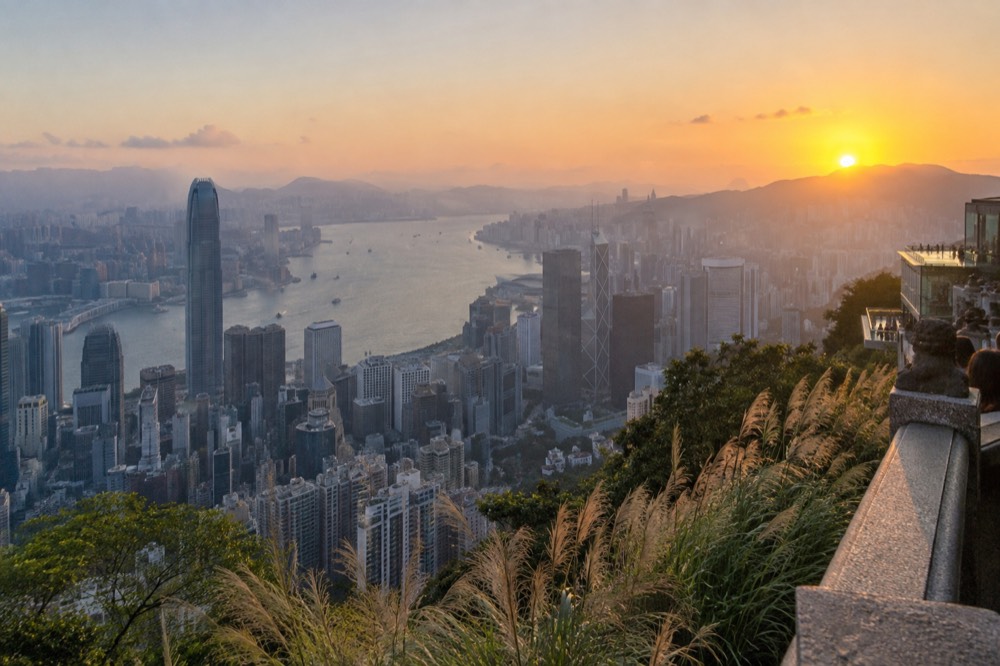 Hong Kong skyline and Victoria Harbour seen from a high hillside at golden hour