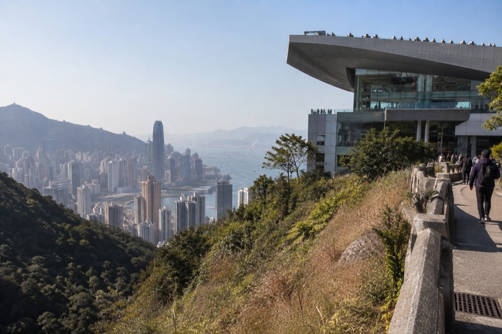 Green hillside above the city with a wok-shaped tower building at Victoria Gap