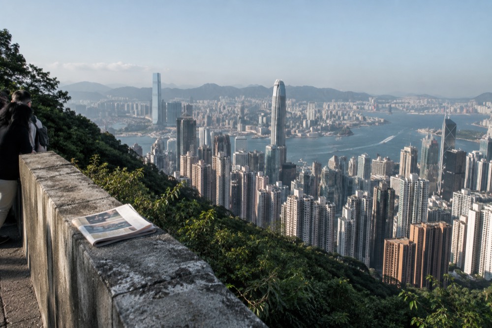 Dense cluster of skyscrapers on Hong Kong Island seen from above with harbour and Kowloon shoreline beyond